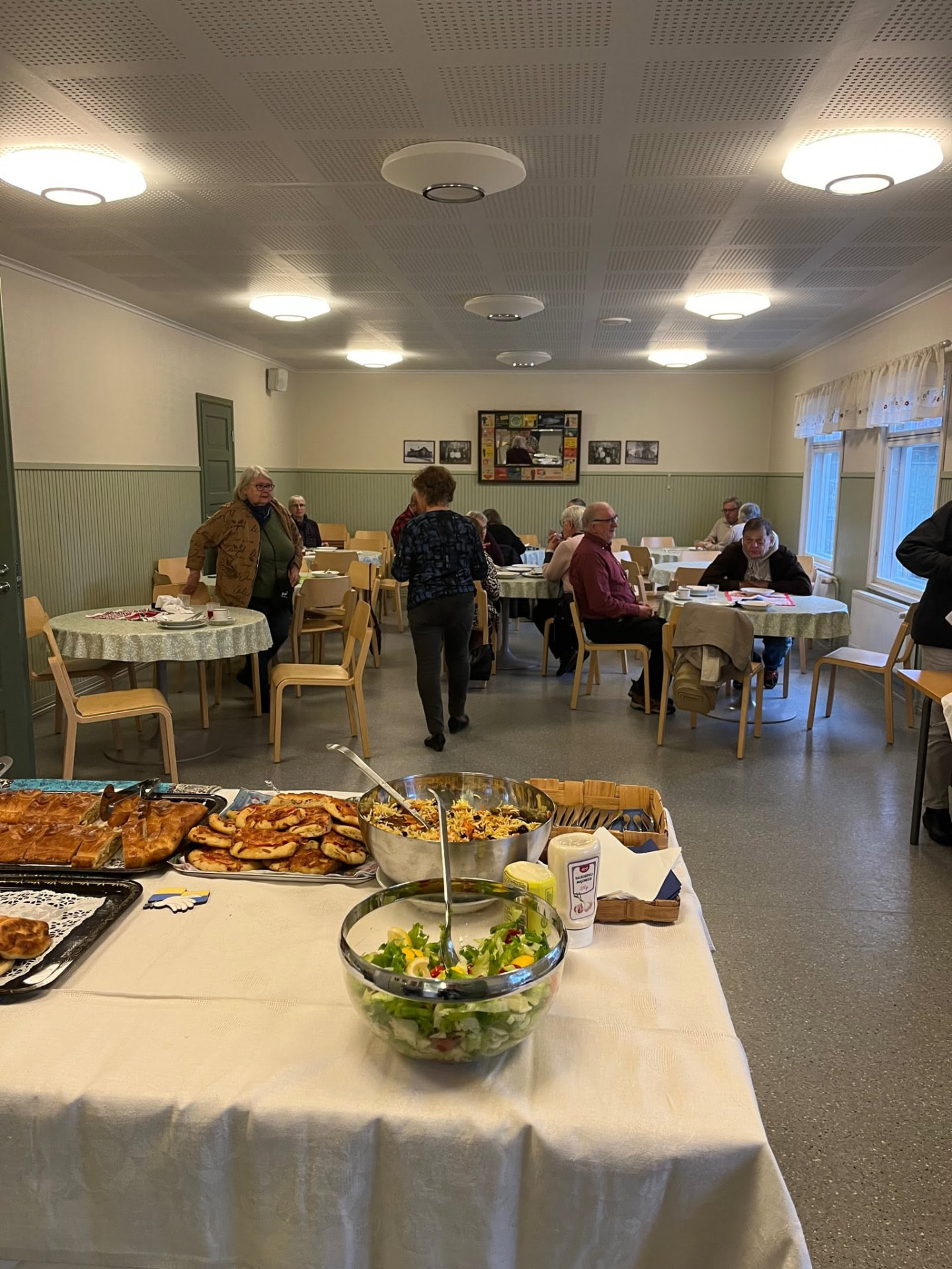 Community members seated at round tables sharing a meal and conversation together